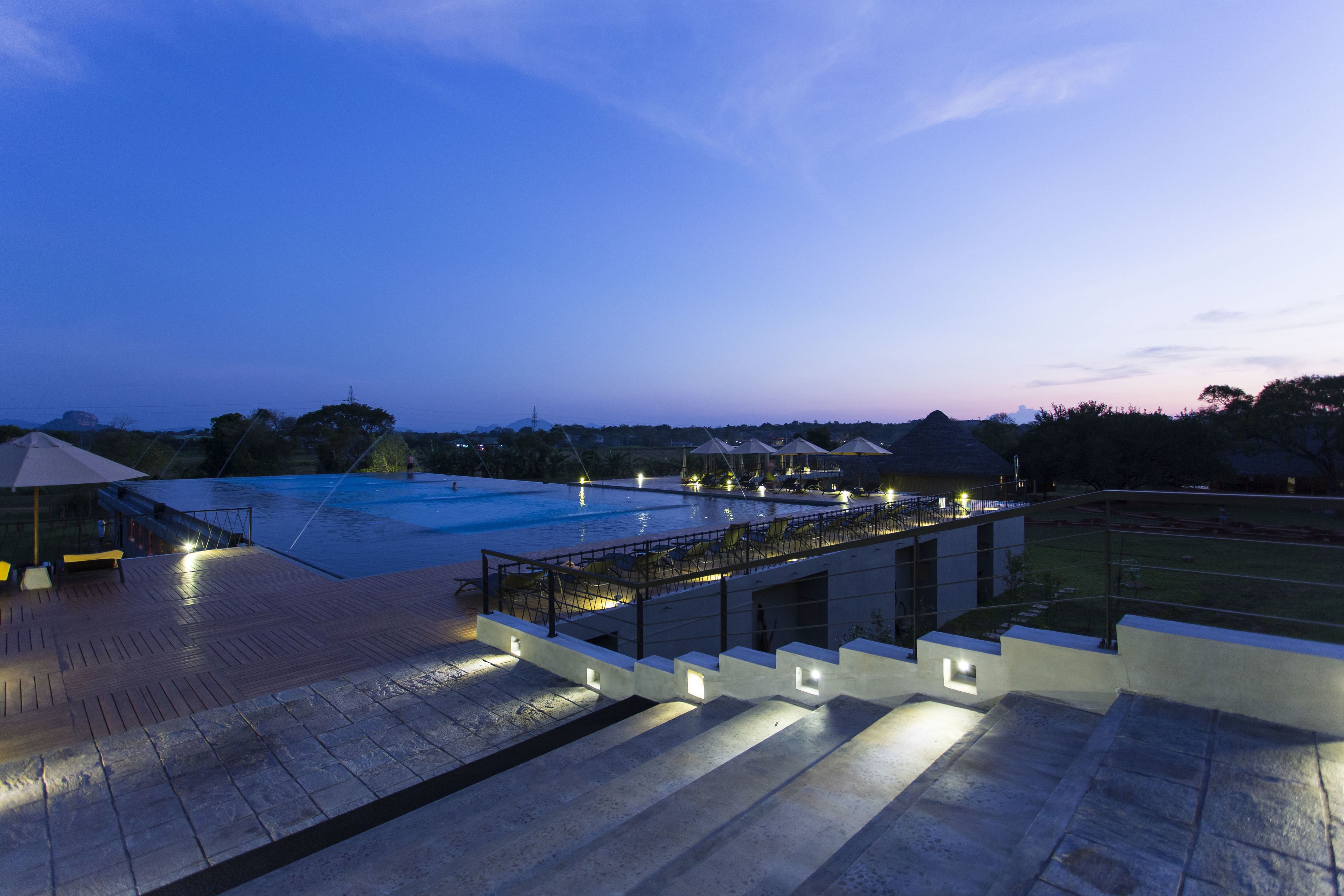 Zona de piscina en la azotea con escalones que bajan a un nivel inferior, rodeada de arquitectura moderna y mobiliario de exterior.