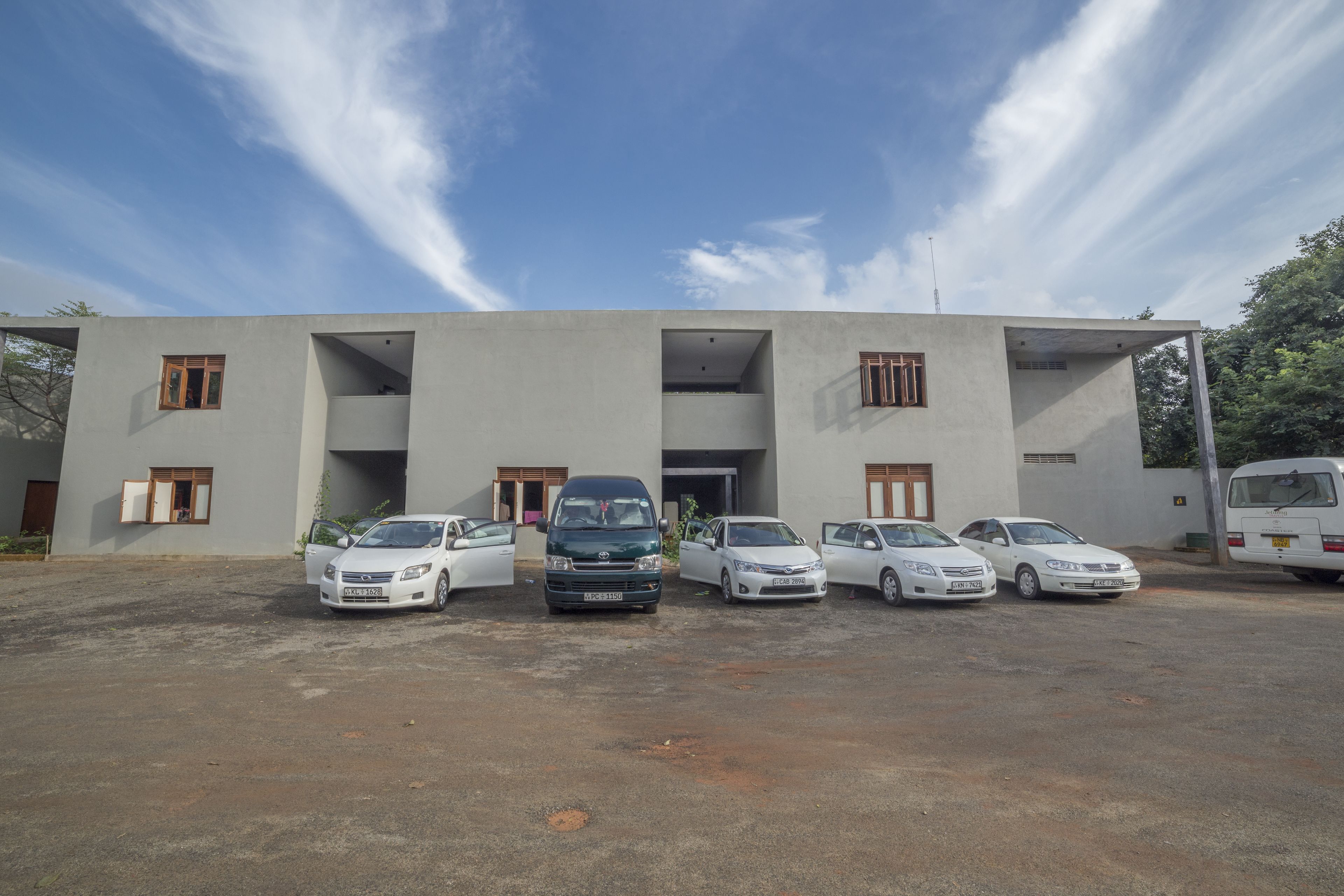 Un edificio moderno con varias entradas y coches estacionados frente a él.