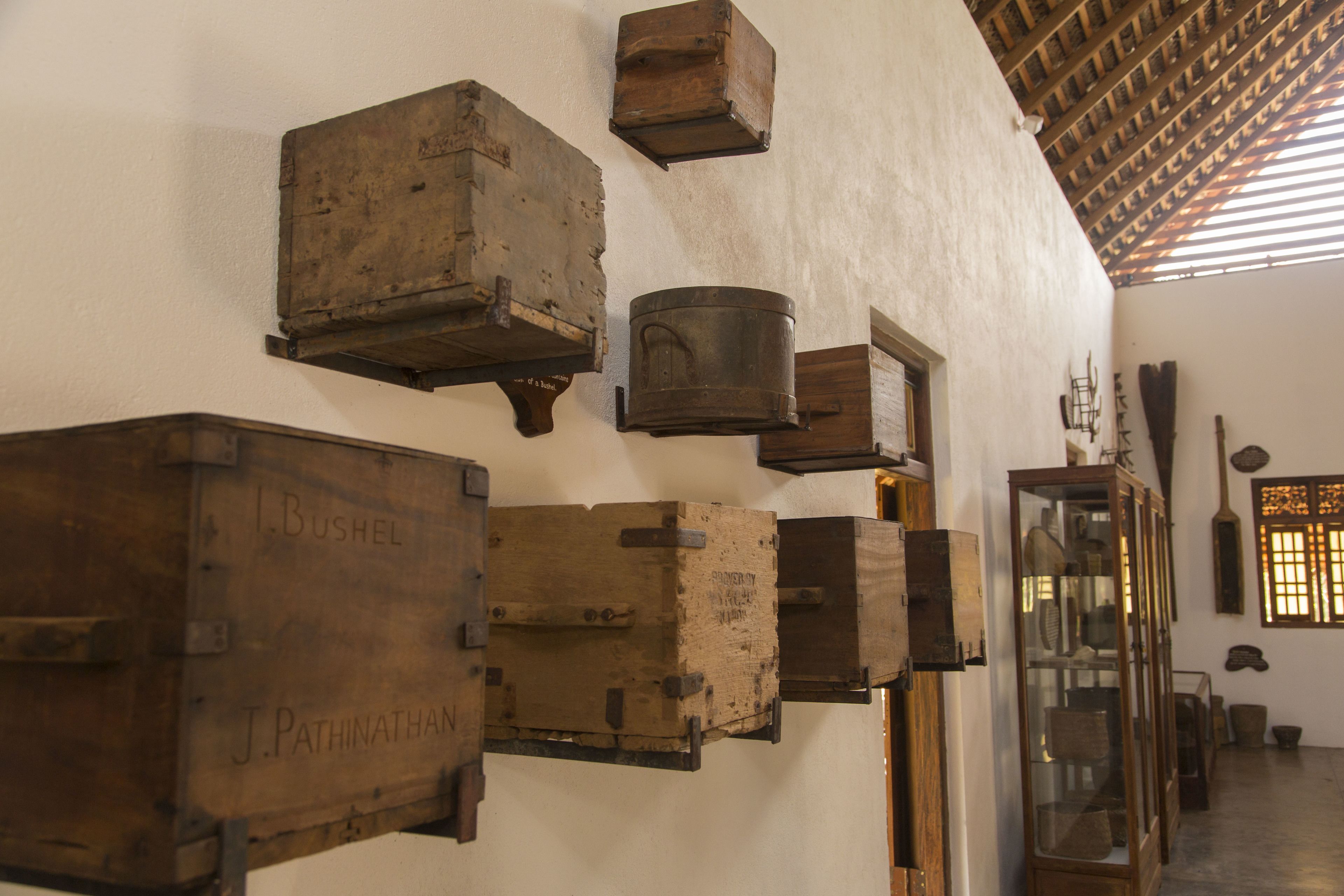 A room with rustic wooden furniture and shelves, including a large wooden chest labeled "J. Pathinatham."