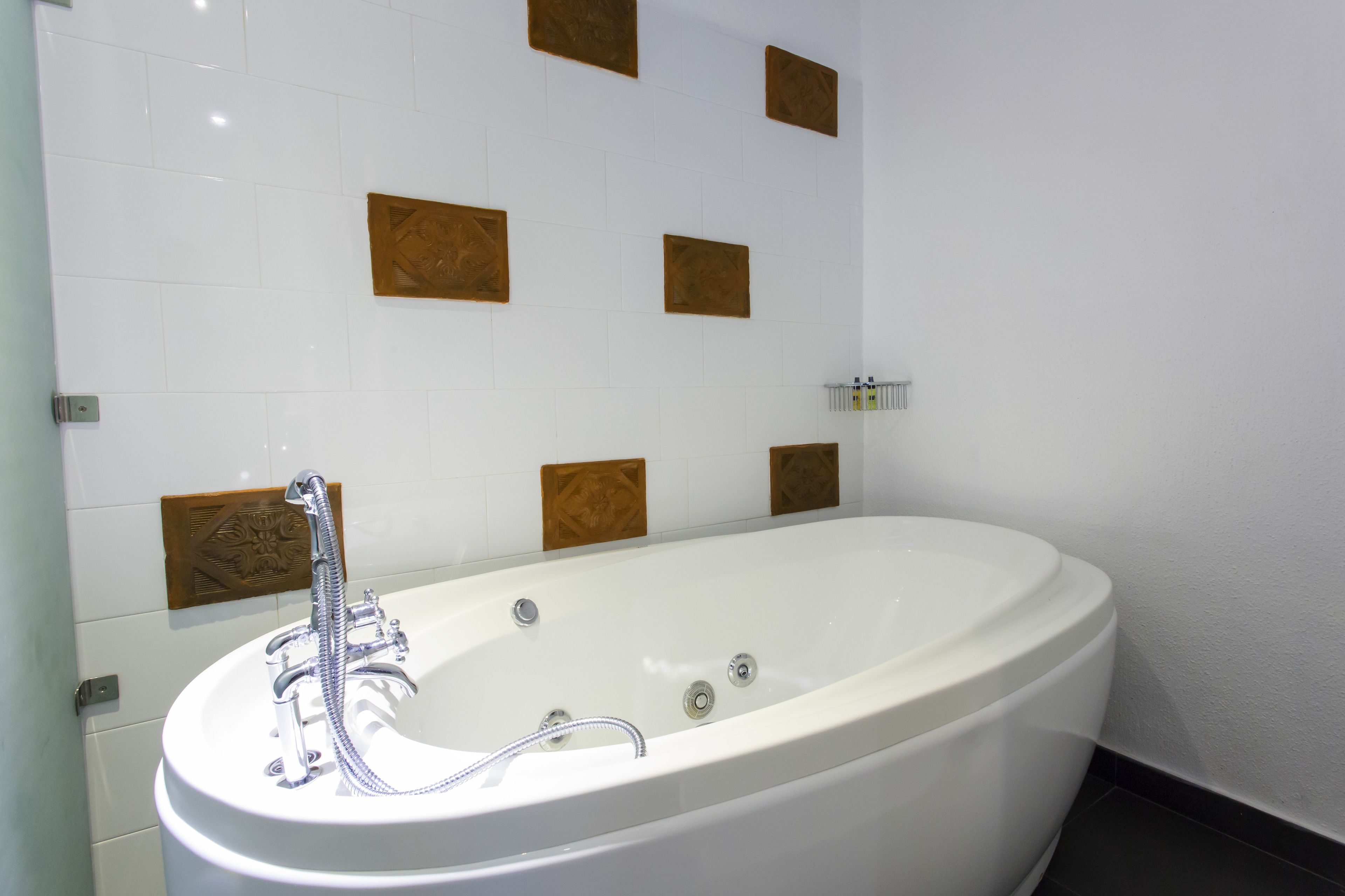A modern bathroom with a freestanding bathtub, white tiles, and decorative wooden panels on the wall.