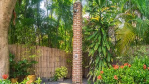A garden with a brick pillar, various plants, and a wooden fence. - Coconut Paradise Villas (Rawai)
