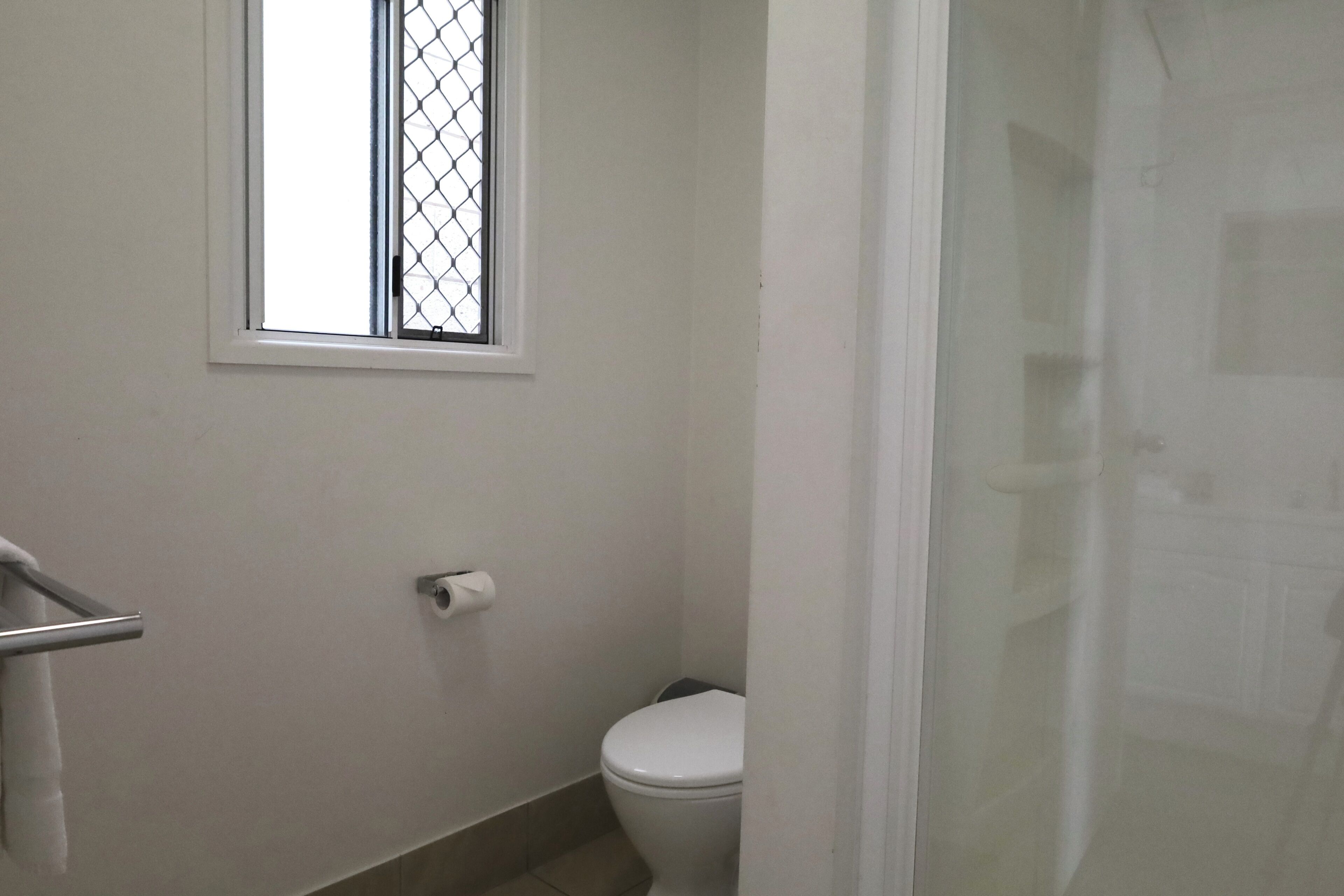 A small bathroom with a toilet, a window, and a shower curtain.