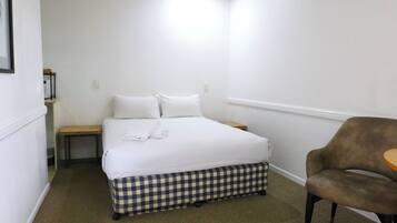 A bedroom with a bed, a chair, a small table, and a bench.