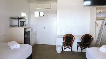 A hotel room with two beds, a desk with a chair, a television, and a wardrobe.