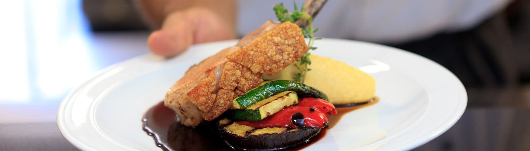 Une assiette comprenant un morceau de poulet grillé, des légumes grillés et une tranche de courge jaune.