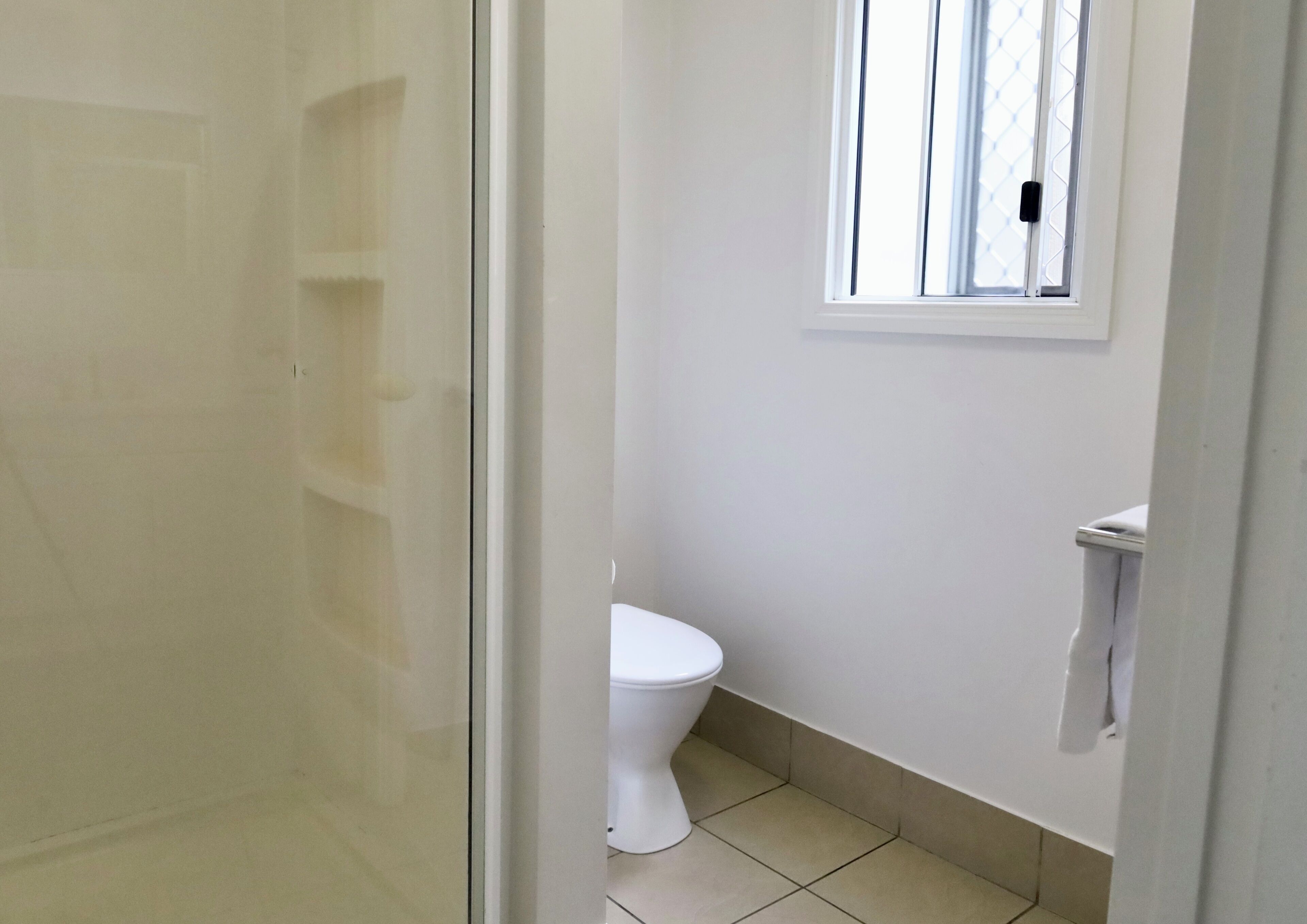 Un baño con inodoro, ventana y zona de ducha.