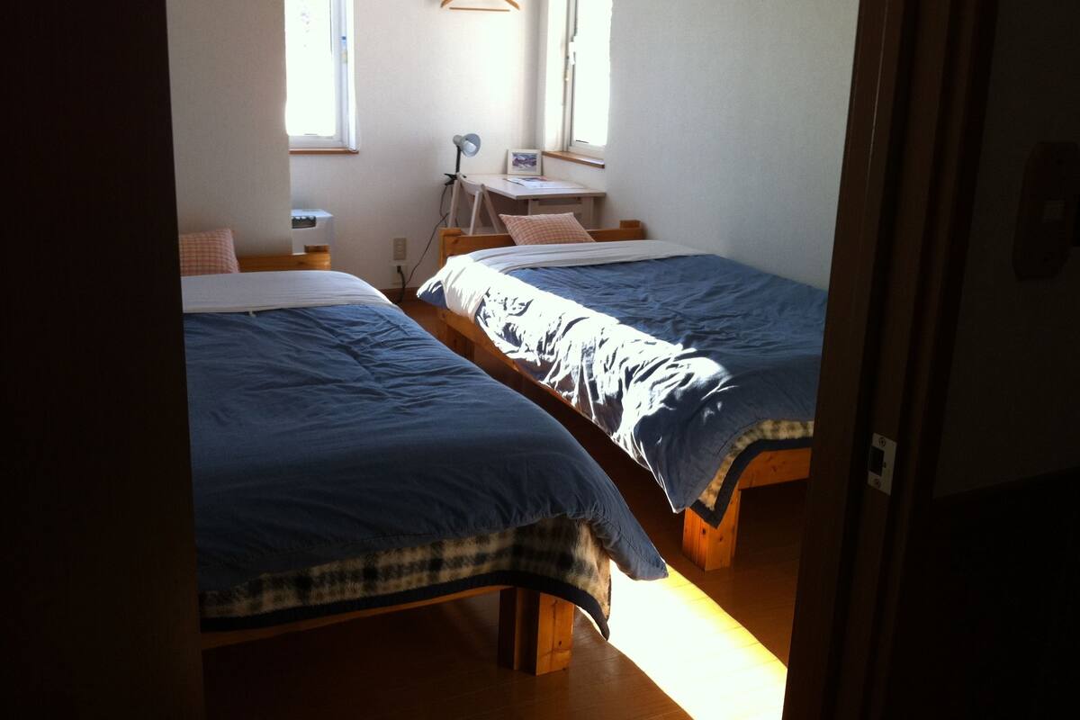 Ein Zimmer mit zwei Betten, einem Schreibtisch und einem Stuhl.