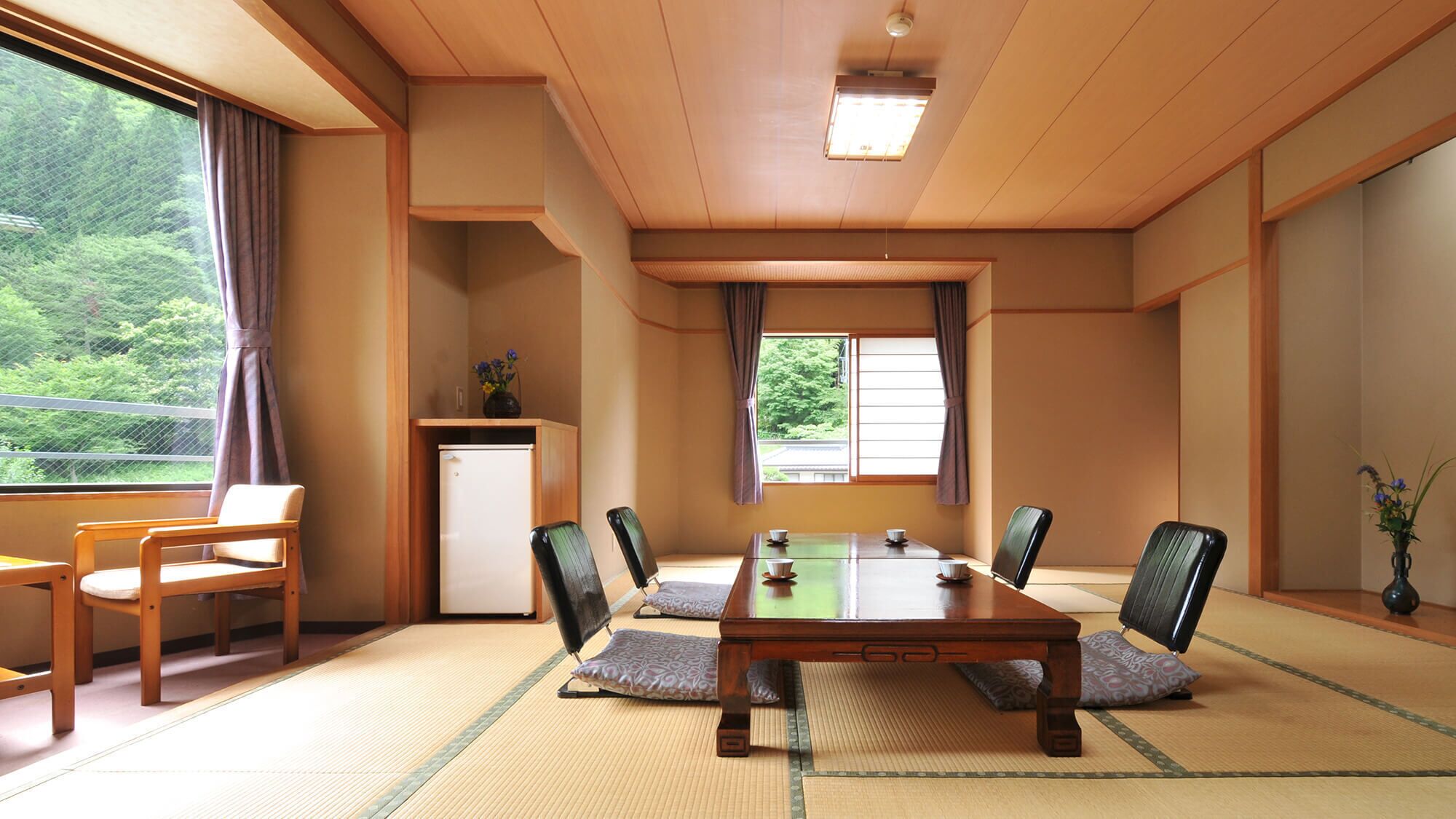 Una habitación de estilo japonés tradicional con suelo de tatami, una mesa baja y sillas.