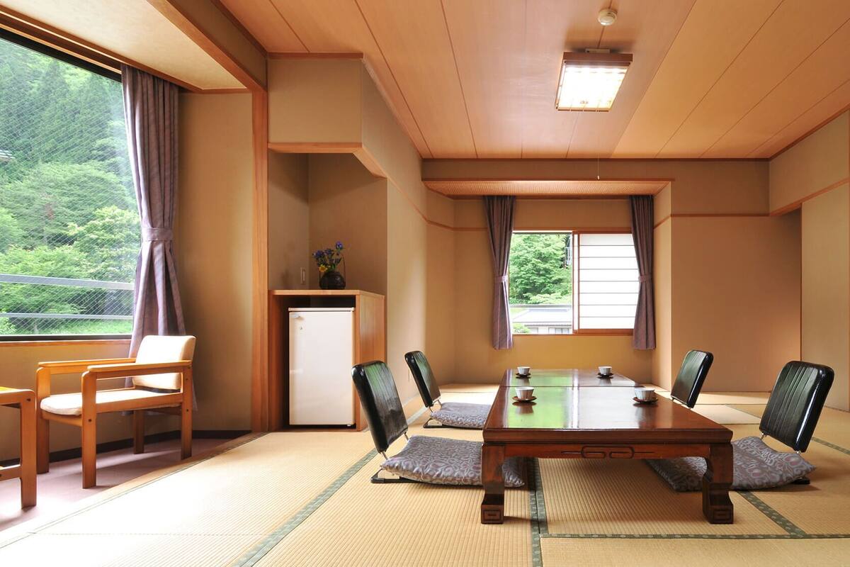 A traditional Japanese-style room with tatami flooring, a low table, and chairs.