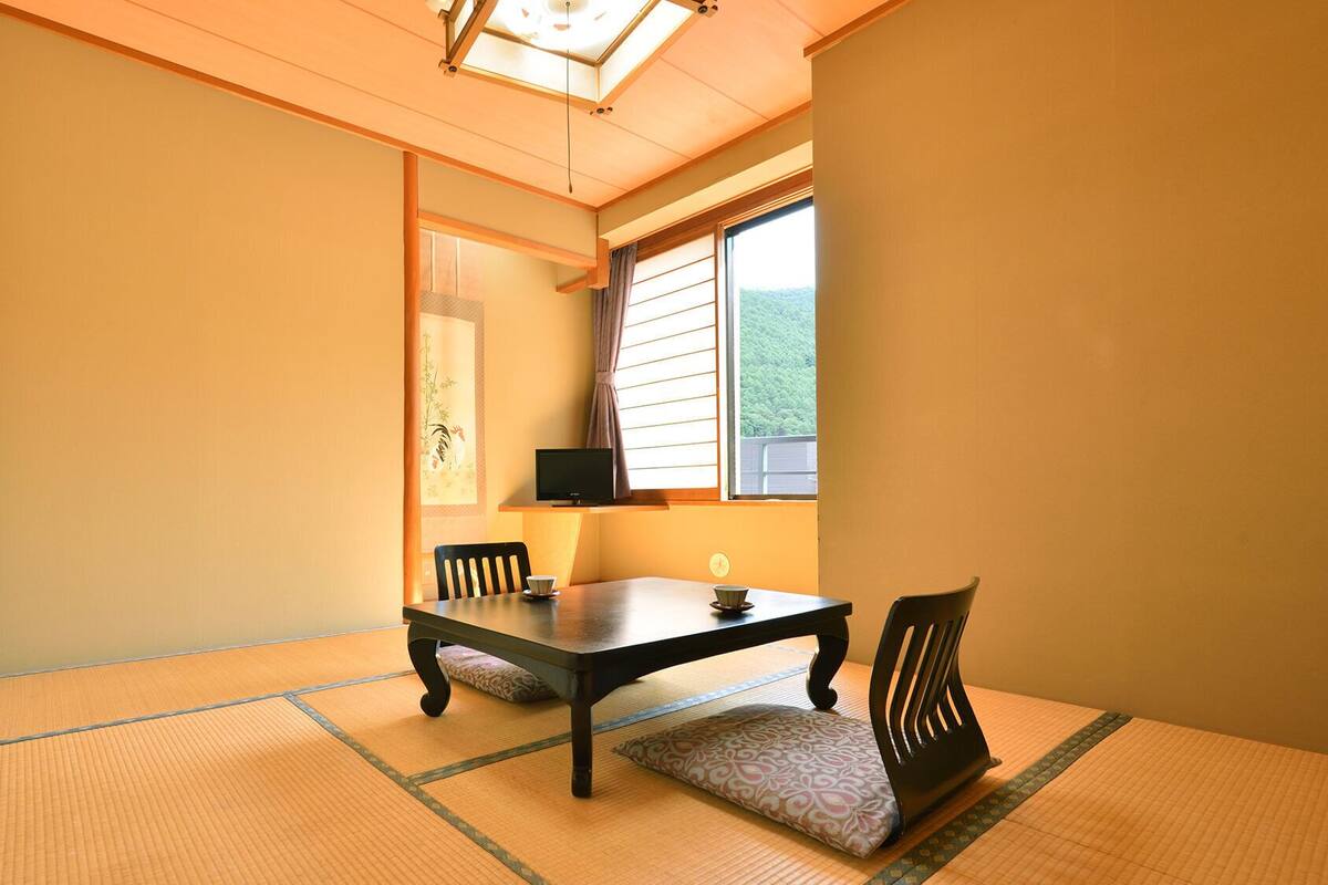 A traditional Japanese room with tatami flooring, a low table, and chairs.
