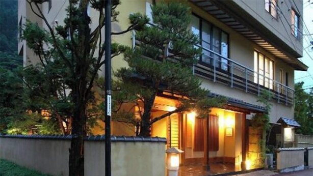 A two-story building with a balcony, a well-lit entrance, and a small garden area. - Bozantei Kotobuki (Ueda)