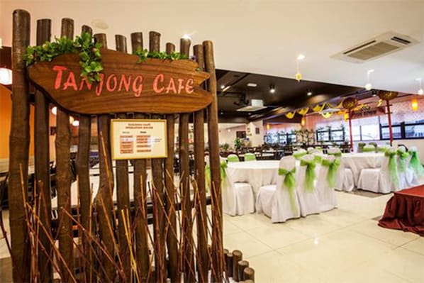 A restaurant with a wooden sign reading "Tanjong Cafe" and tables set for dining.