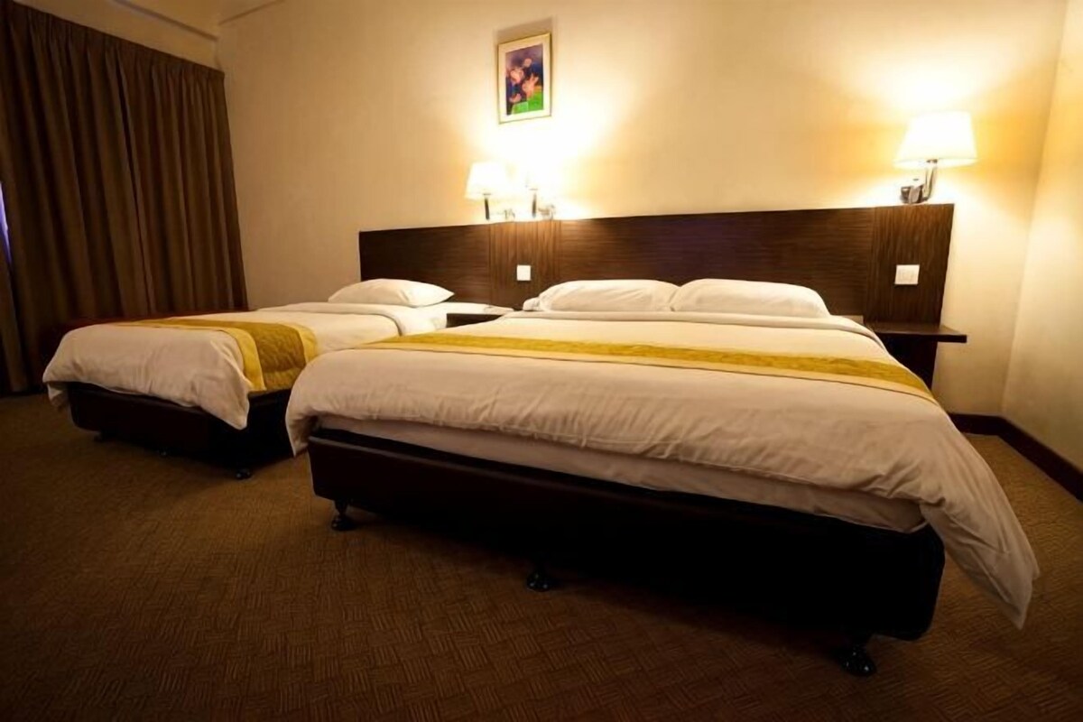 Una habitació d'hotel amb dos llits, un capçal, làmpades de nit i un quadre a la paret.