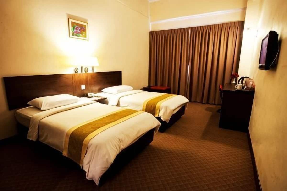 Habitación de hotel con dos camas, cabecero, mesita de noche, escritorio, silla, televisor y ventana con cortinas.