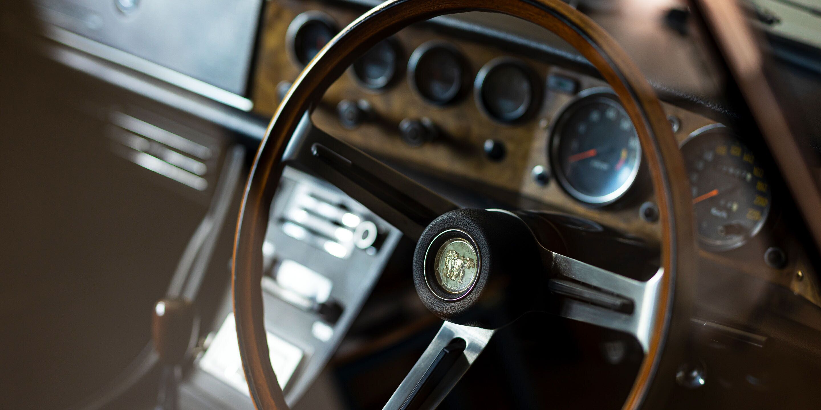 A vintage car's interior with a steering wheel, dashboard, and speedometer.