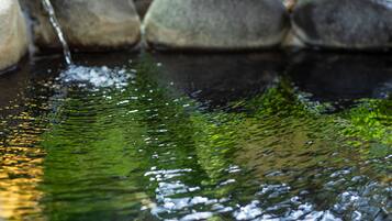 A stream flowing over rocks with clear water reflecting the surrounding environment.