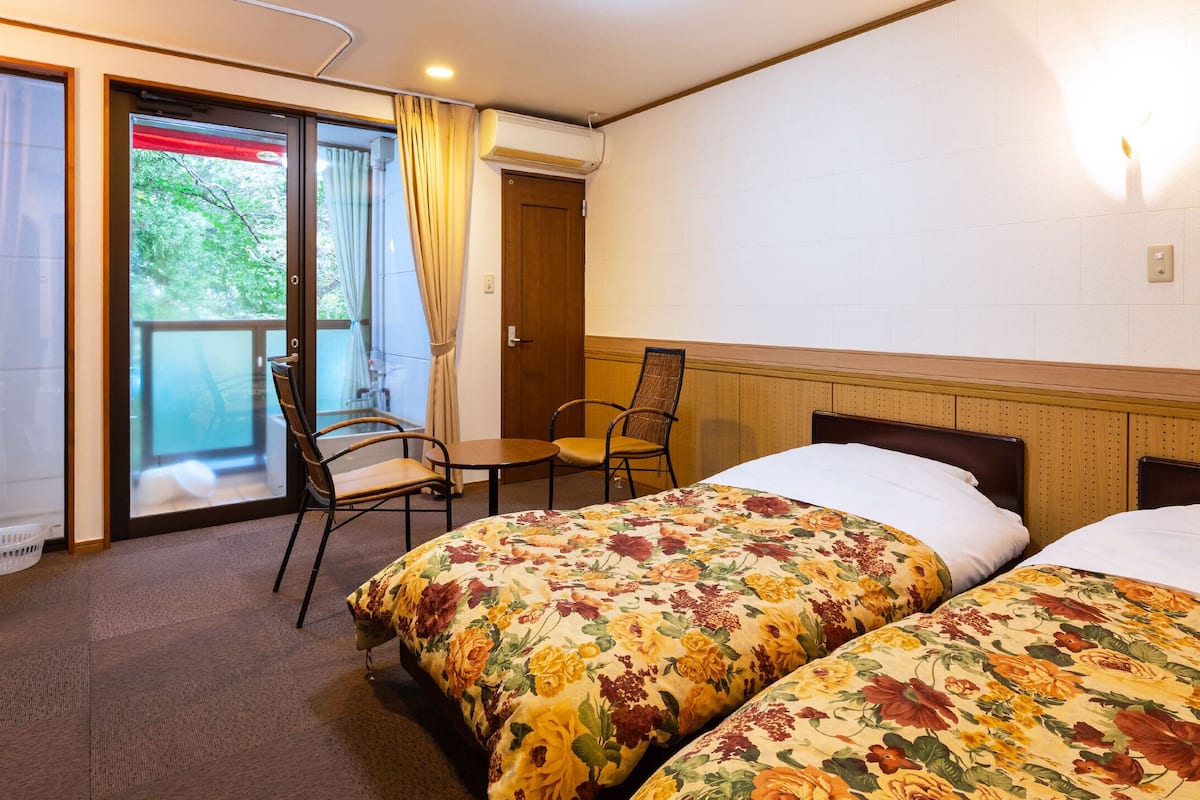 A hotel room with two beds, a desk, and a chair.