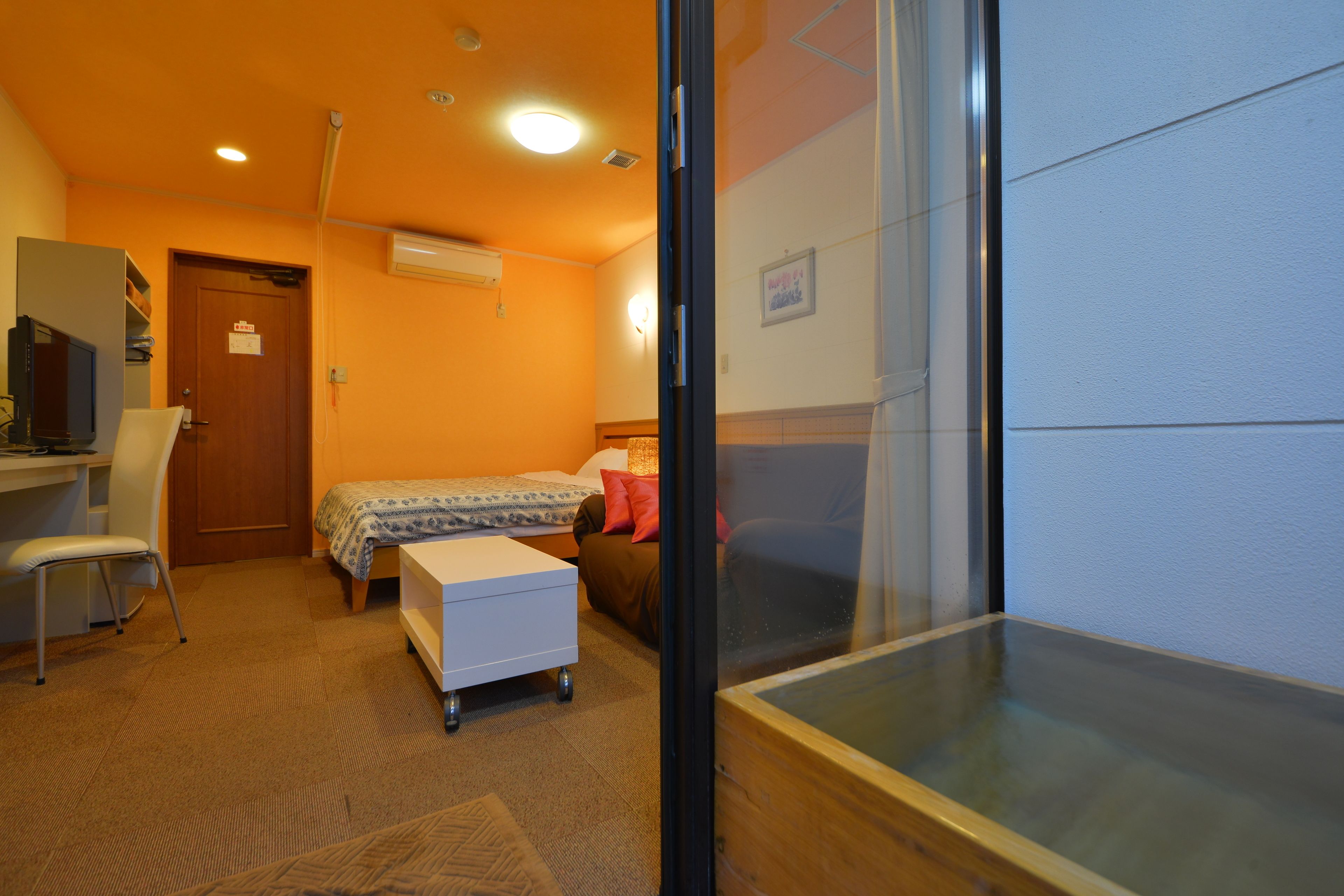 A room with a bed, a desk, a chair, and a small table.