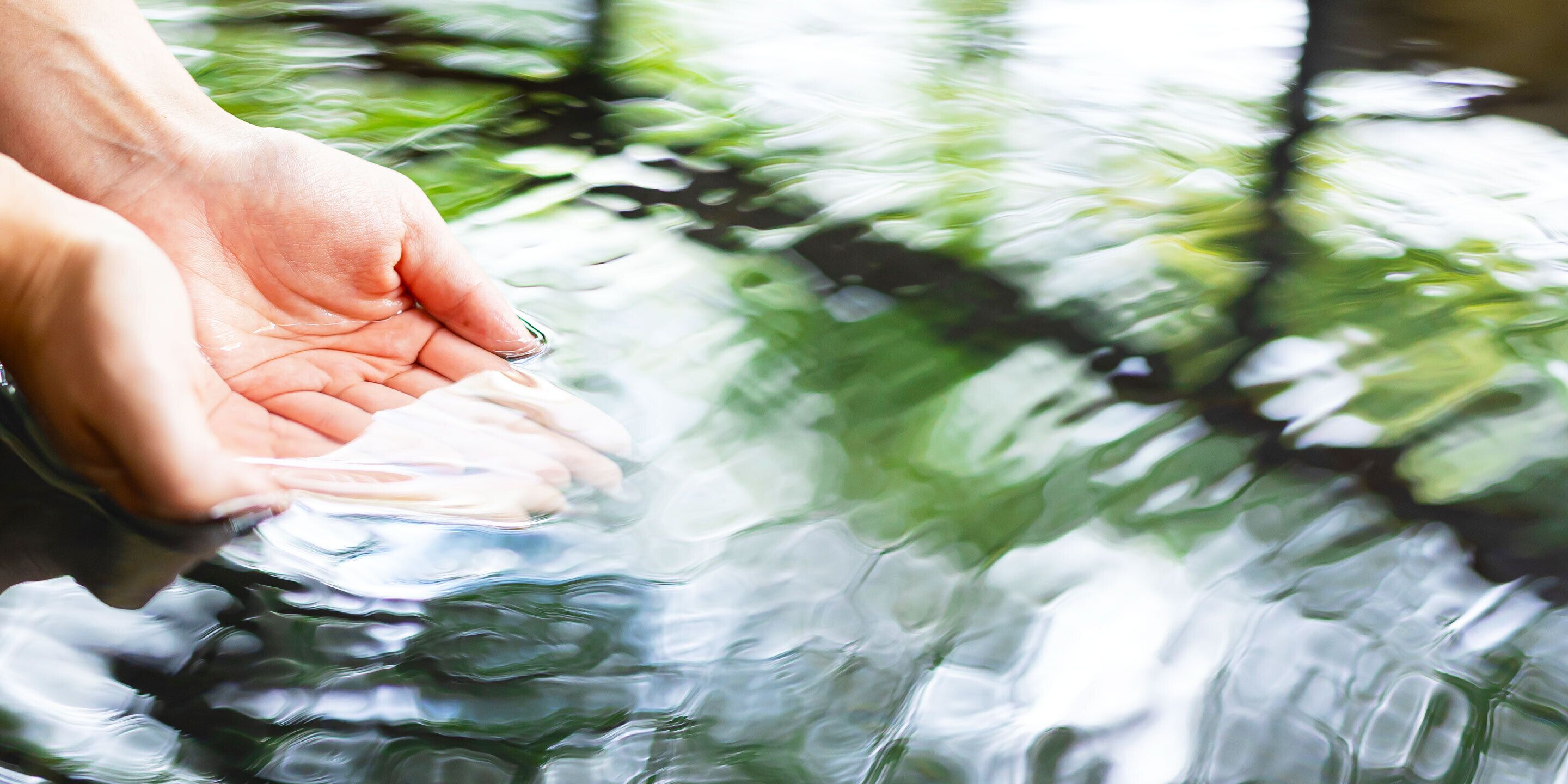 A hand holding a clear glass of water.
