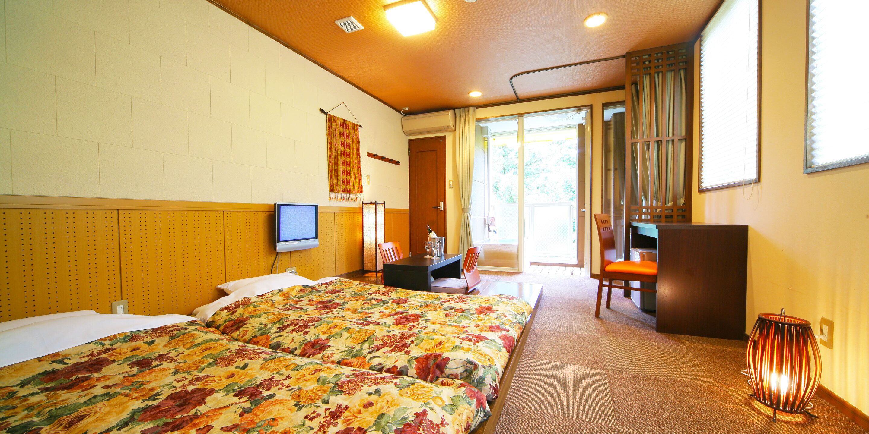 A hotel room with two beds, a television, a desk, and a chair.