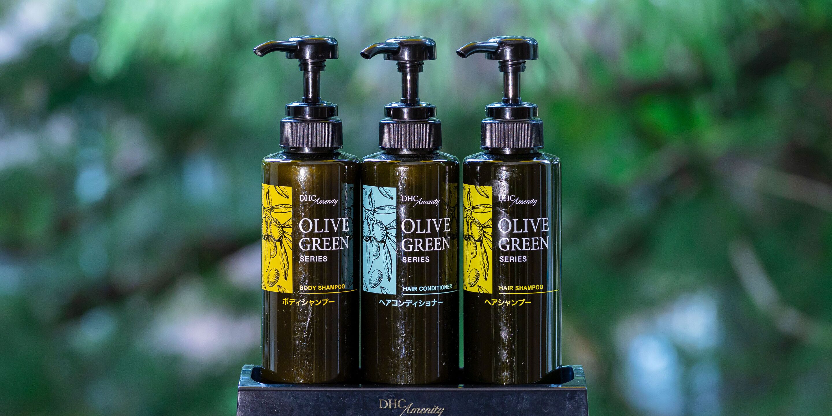 Three bottles of Olive Green Series hair products on a display stand.