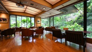 Una habitación amplia con suelo de madera, ventanas grandes y vista a vegetación exuberante.