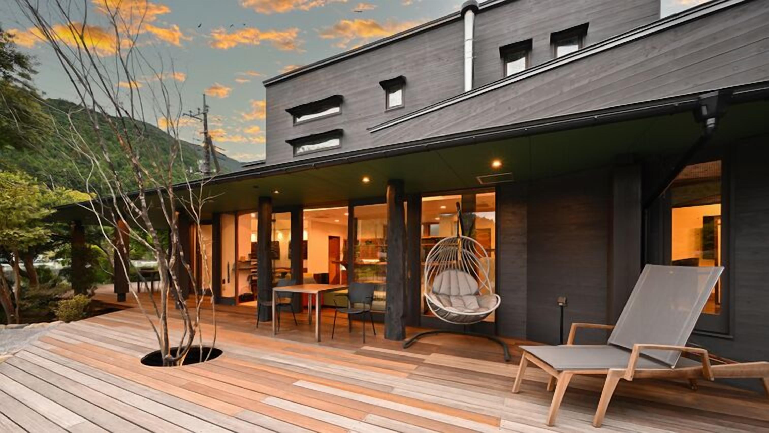 Ein modernes Gebäude mit einer Holterrasse, Sitzgelegenheiten im Freien und einem Hängestuhl.