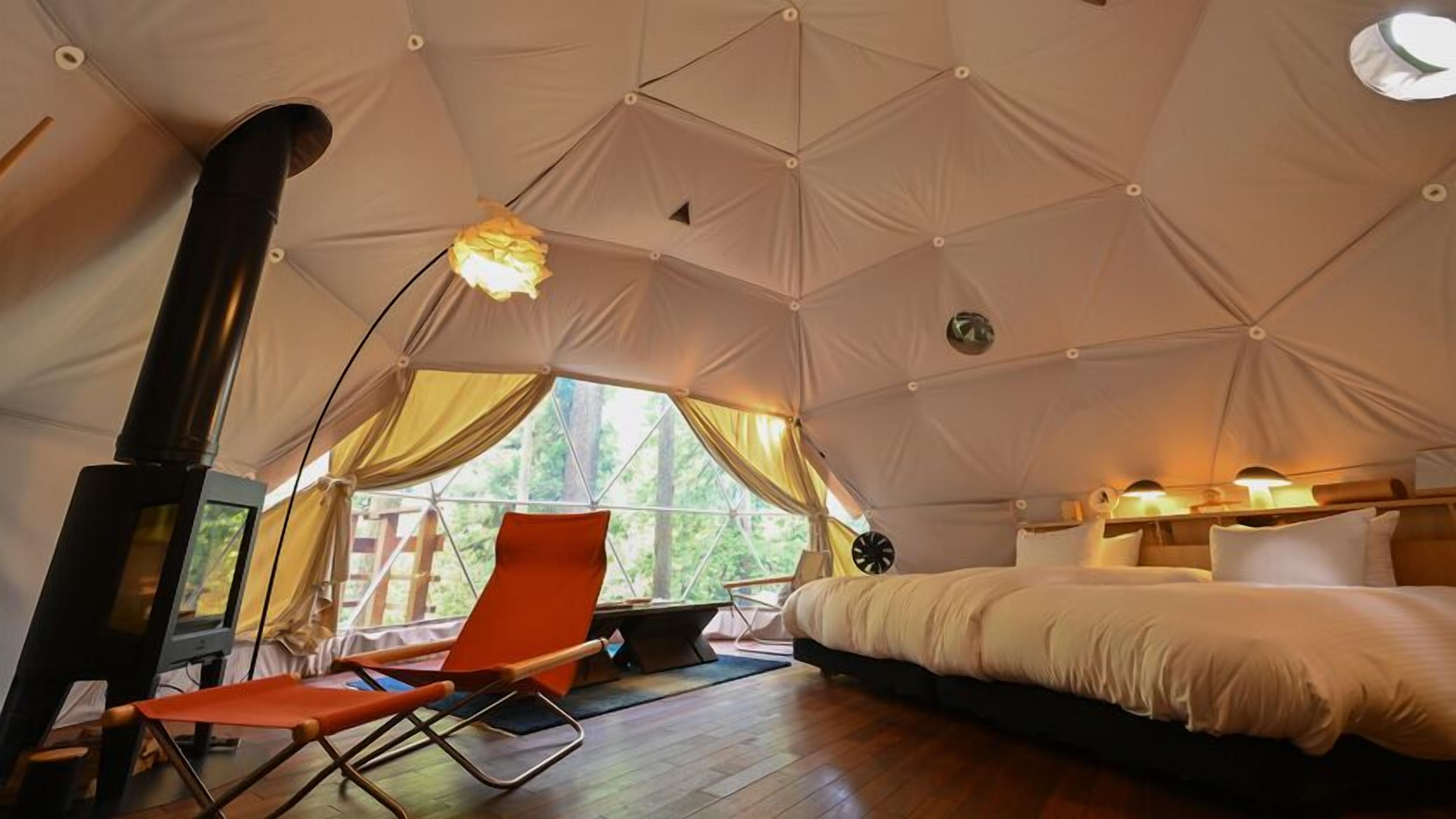 Ein Zelt mit Bett, Stuhl, Tisch und Kamin.