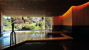 A modern spa with a large window, a wooden ceiling, and a view of a garden. - Naguri Onsen Taishokaku (Hanno)