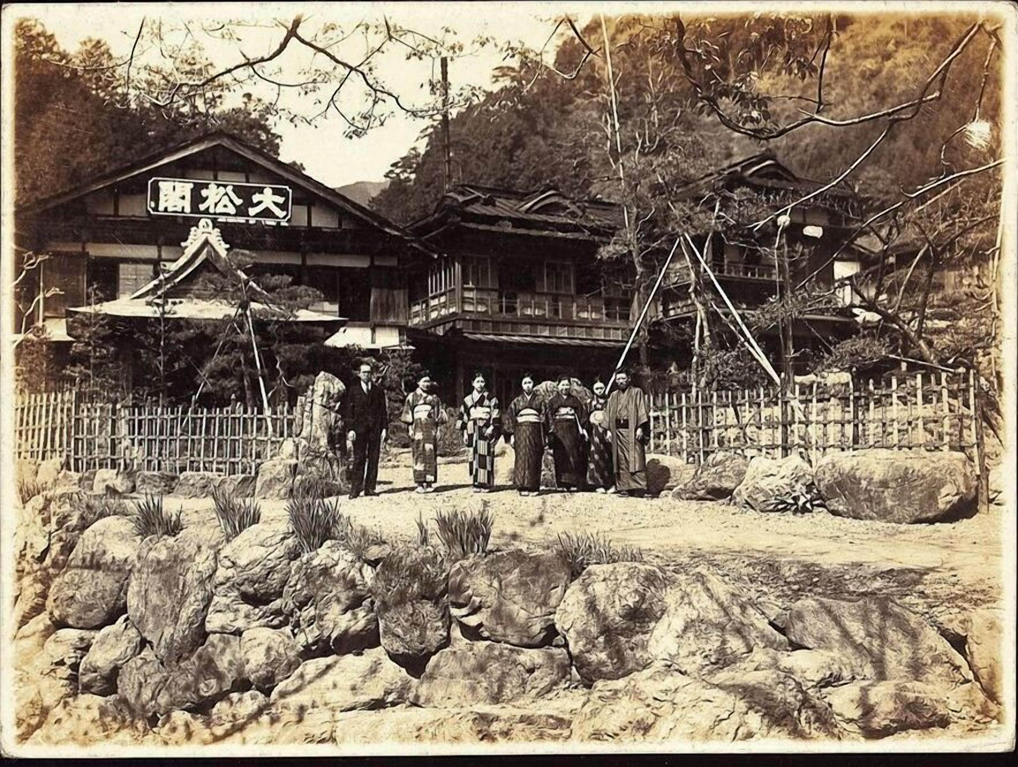 Un edificio japonés tradicional de estructura de madera, un letrero y un camino de piedra.