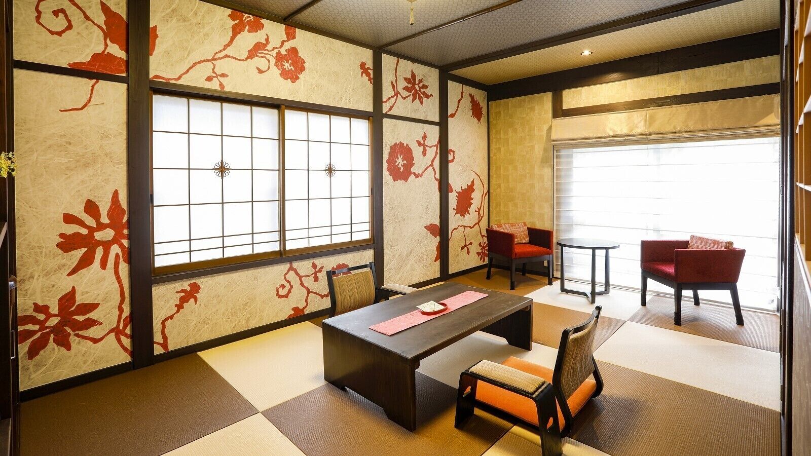Una habitación al estilo japonés tradicional, con suelo de tatami, una mesa baja y sillas rojas.