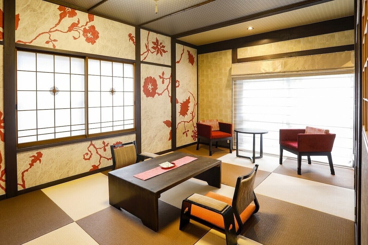 Una habitación al estilo japonés tradicional, con suelo de tatami, una mesa baja y sillas rojas.