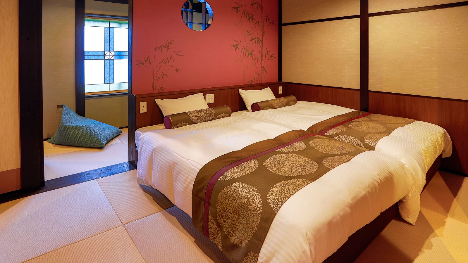 Una habitación tradicional japonesa con suelo de tatami, una cama doble con ropa de cama estampada y una puerta corredera de shoji.