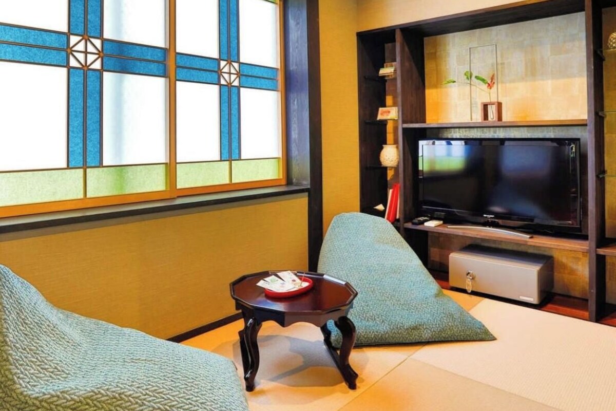 A traditional Japanese-style room with tatami flooring, a low table, and a television.