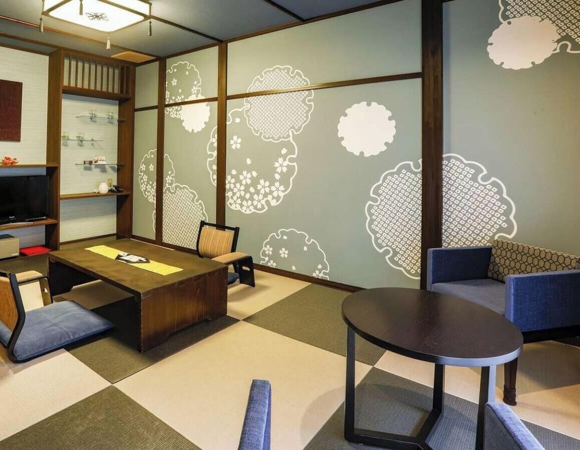A room with tatami flooring, a low wooden table, a sofa, and a television.