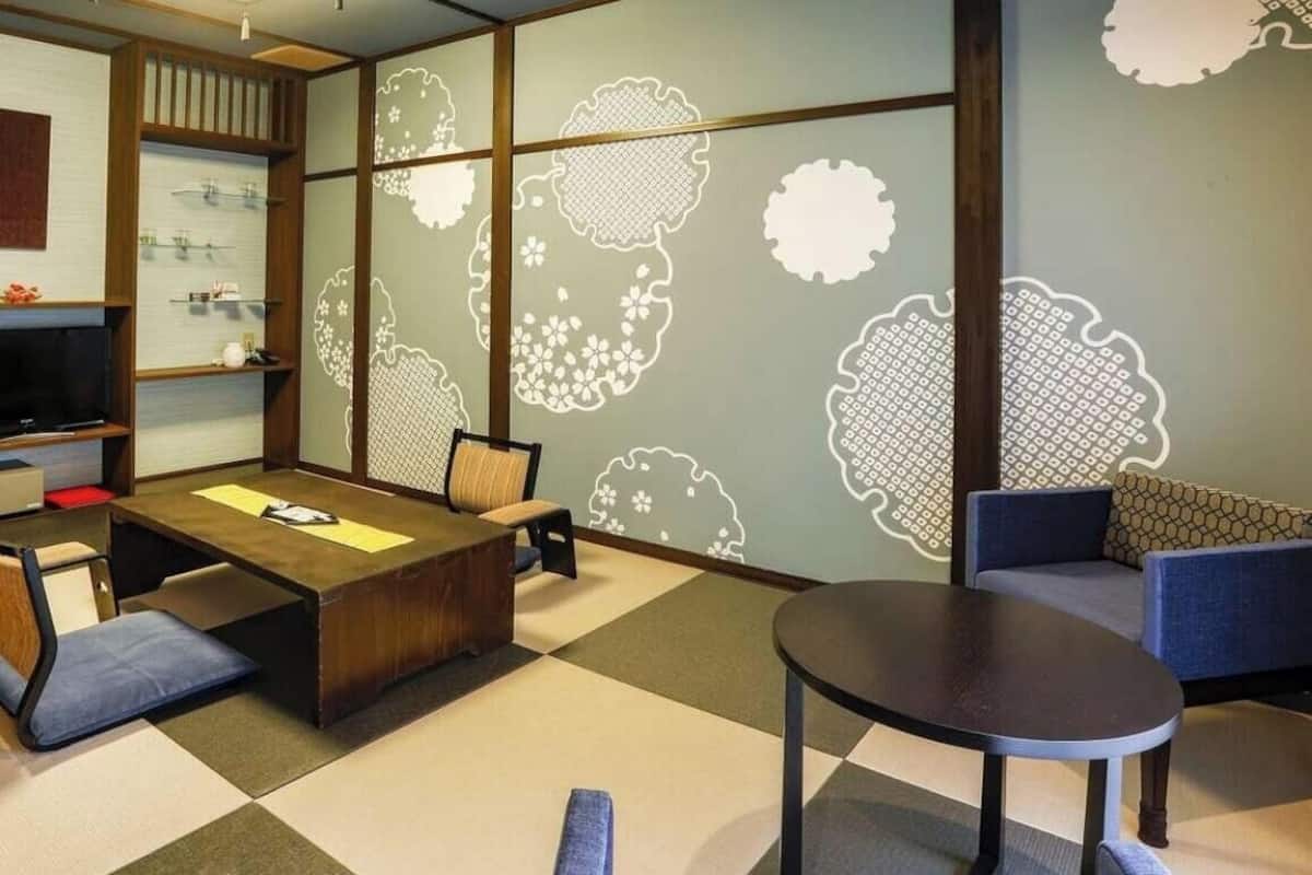 Una habitación con suelo de tatami, una mesa de madera baja, un sofá y un televisor.