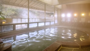 Un bain dans une source thermale, avec vue sur un paysage rocheux grâce à de grandes fenêtres.