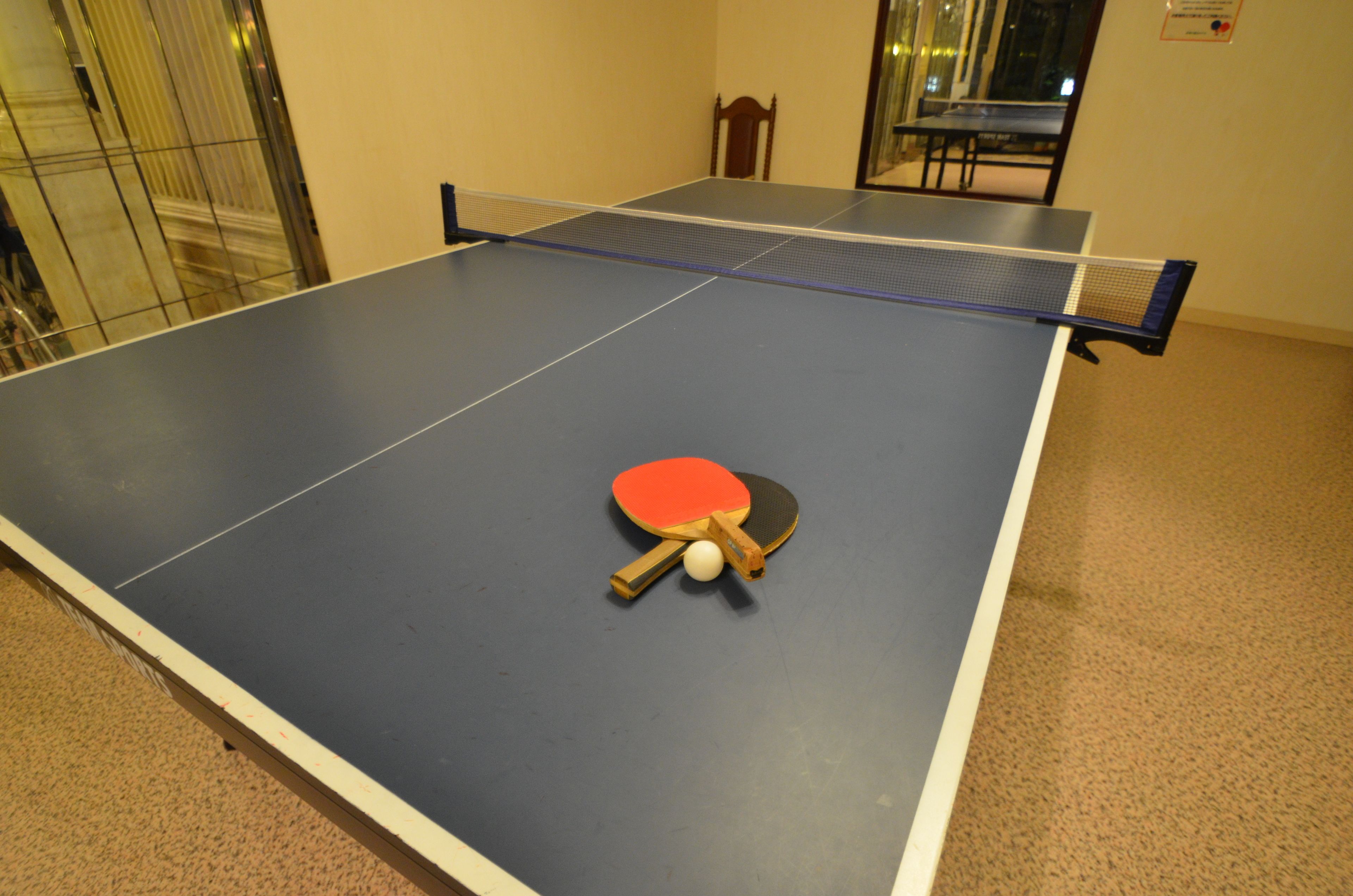 A ping pong table with a paddle and ball in the center.