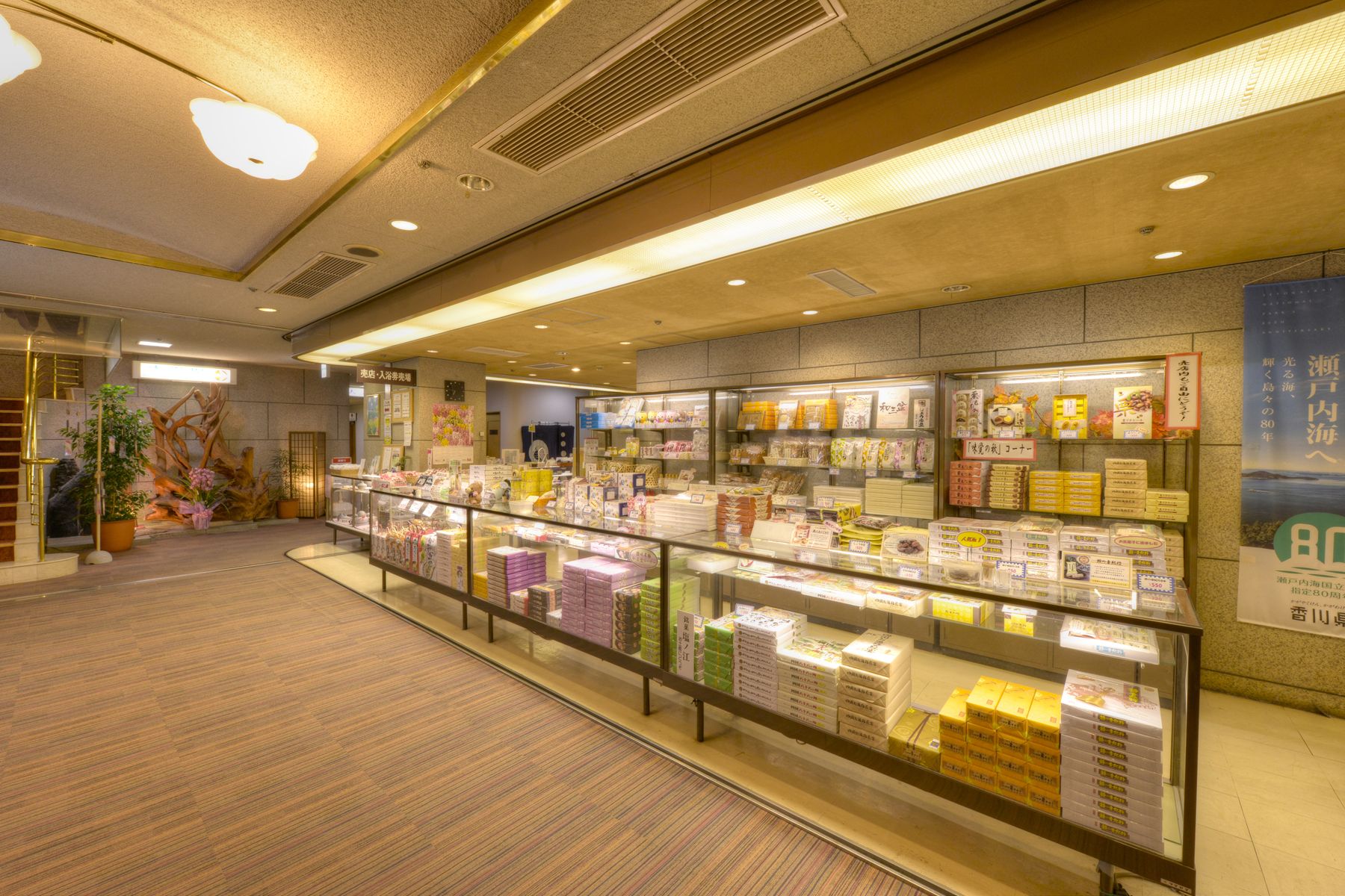 A bookstore with shelves of books and magazines, a staircase, and a display case with items.