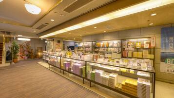 A bookstore with shelves of books and magazines, a staircase, and a display case with items.