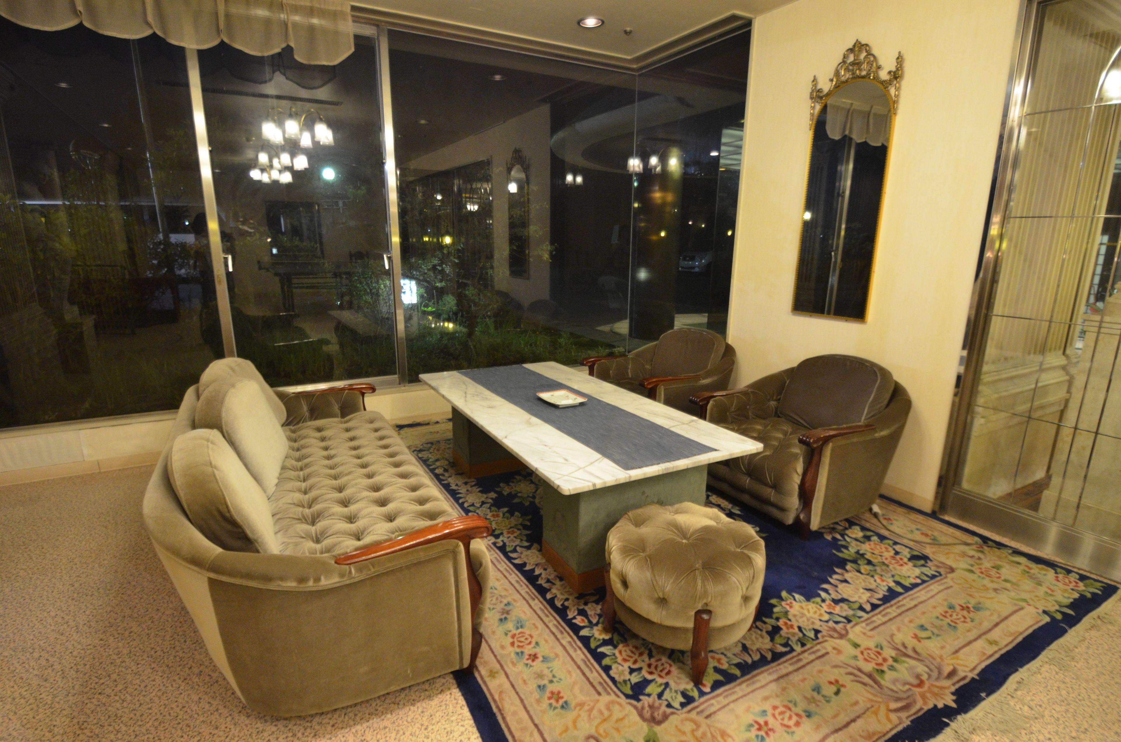 Un salón con sofá, sillones, una mesa de centro y un ventanal grande.