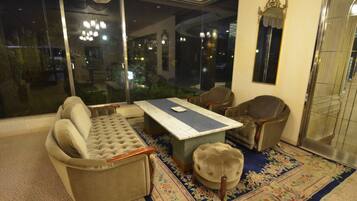 Un salón con sofá, sillones, una mesa de centro y un ventanal grande.