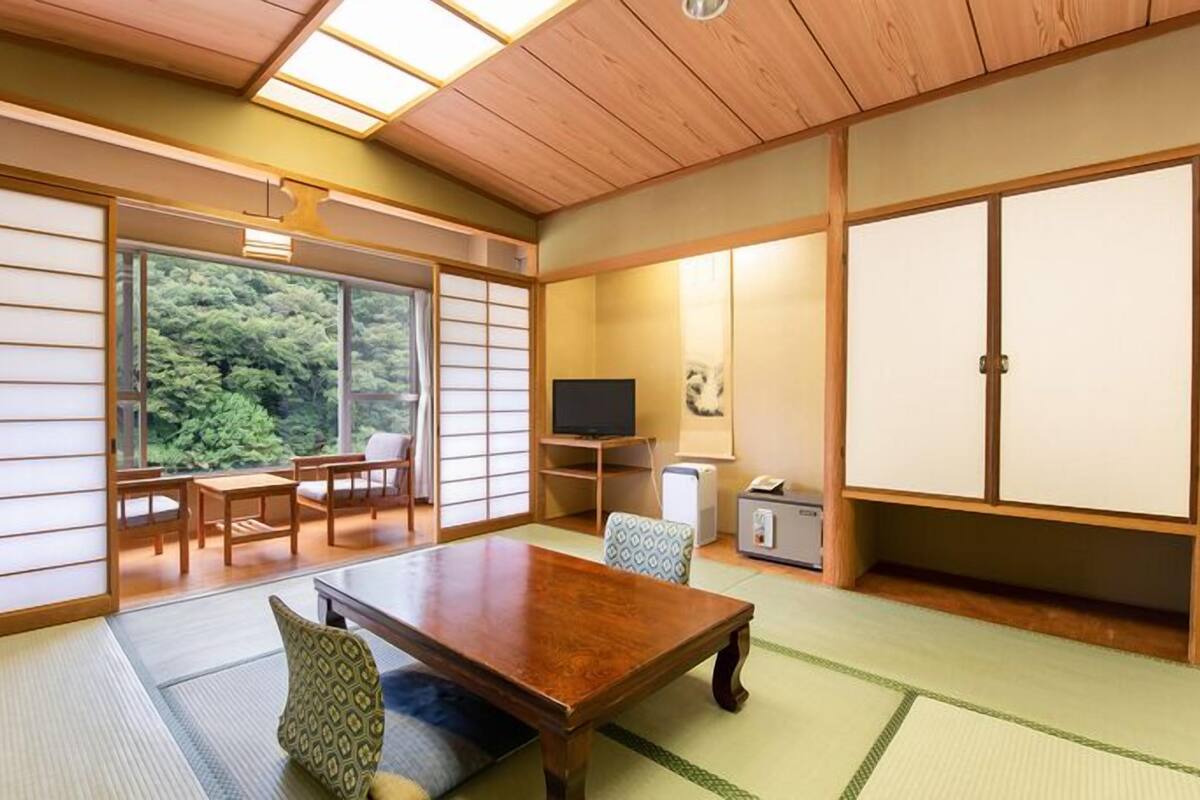 Een traditionele Japanse kamer met tatami vloerbedekking, een lage tafel en schuifdeuren.