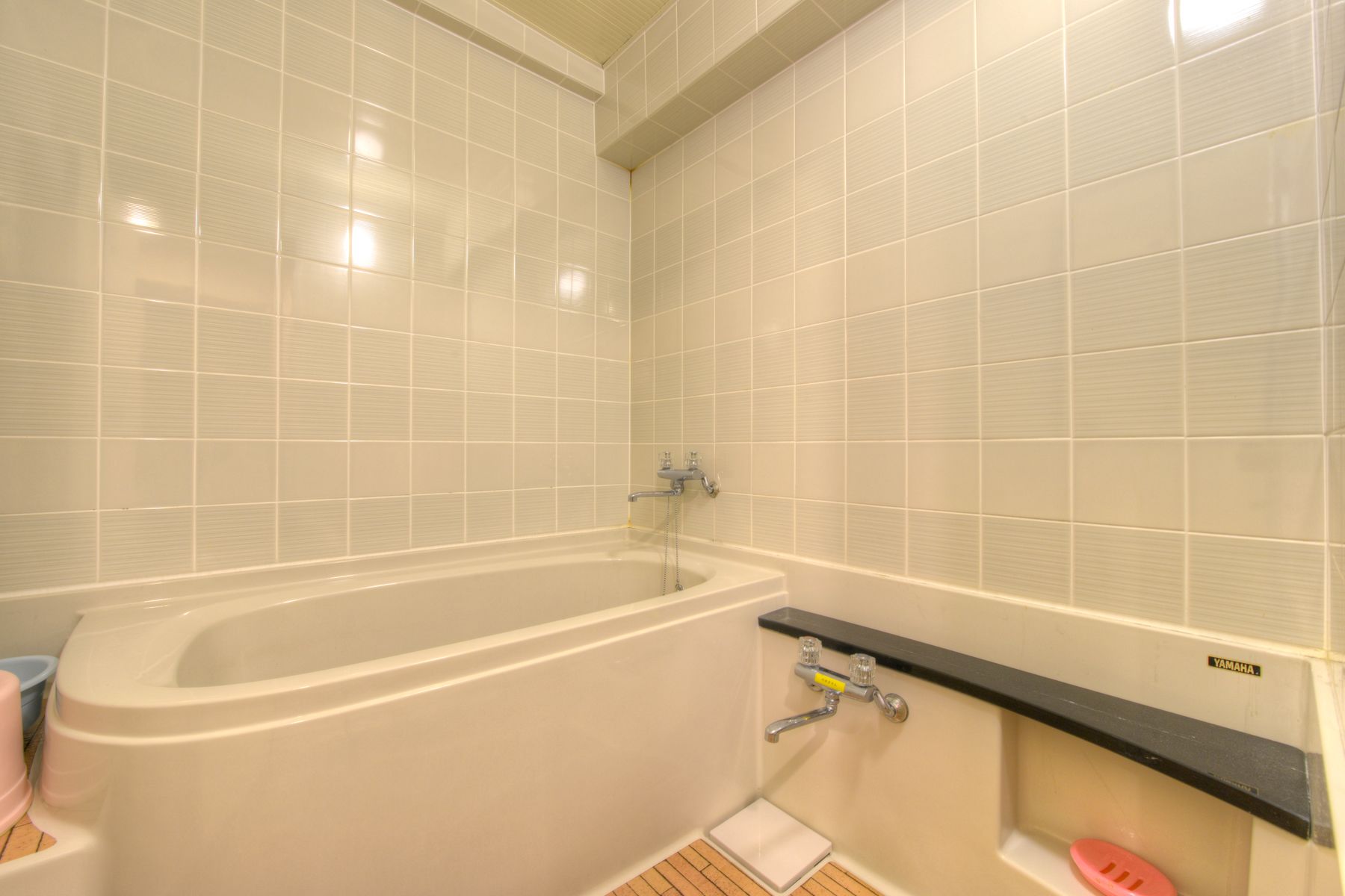 A bathroom with a bathtub, a toilet, and a shelf with toiletries.