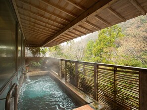 A wooden deck with a hot spring bath, surrounded by a bamboo fence and trees. - Shin Kabakawa Kanko Hotel (Takamatsu)