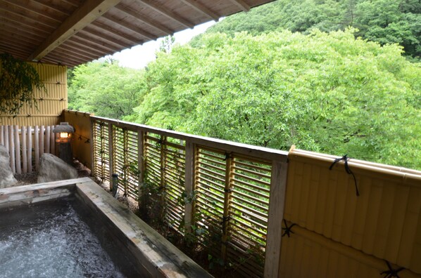 A wooden balcony with a view of lush green trees. - Shin Kabakawa Kanko Hotel (Takamatsu)