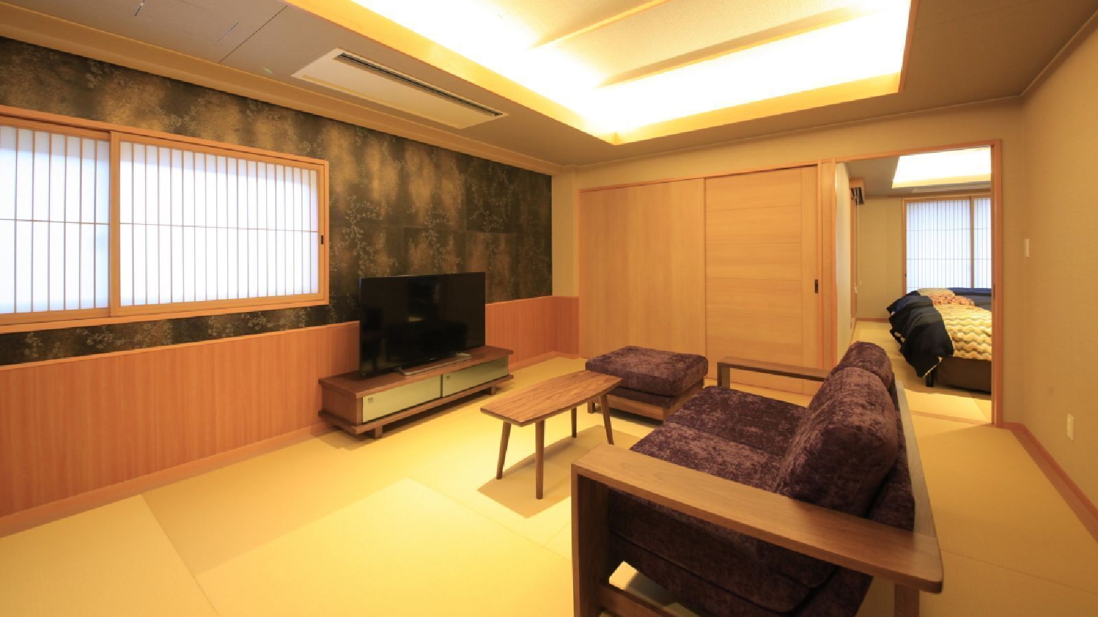 Un saló tradicional japonès amb tatami, una taula de fusta baixa, un sofà i una televisió.