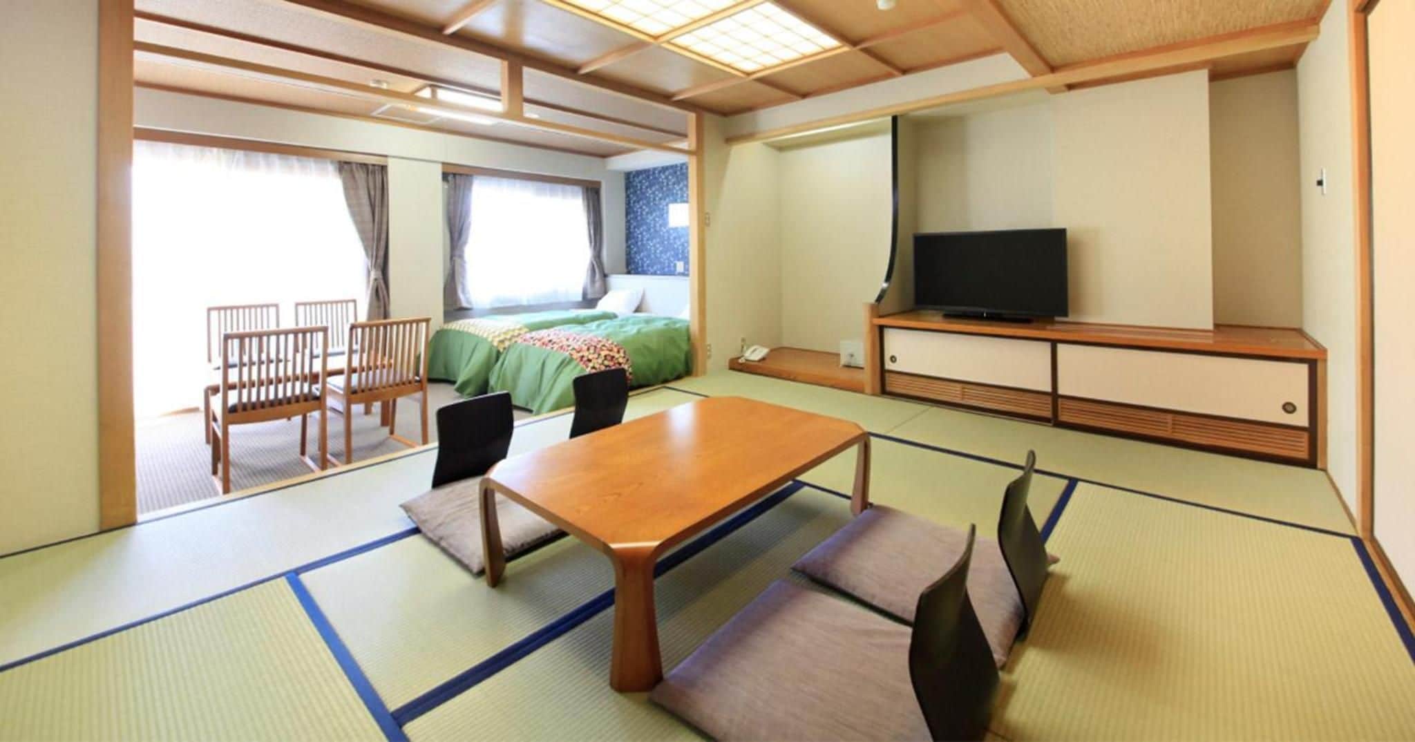 Ein Zimmer mit einem Bett, einem Fernseher, einem Esstisch und Stühlen.