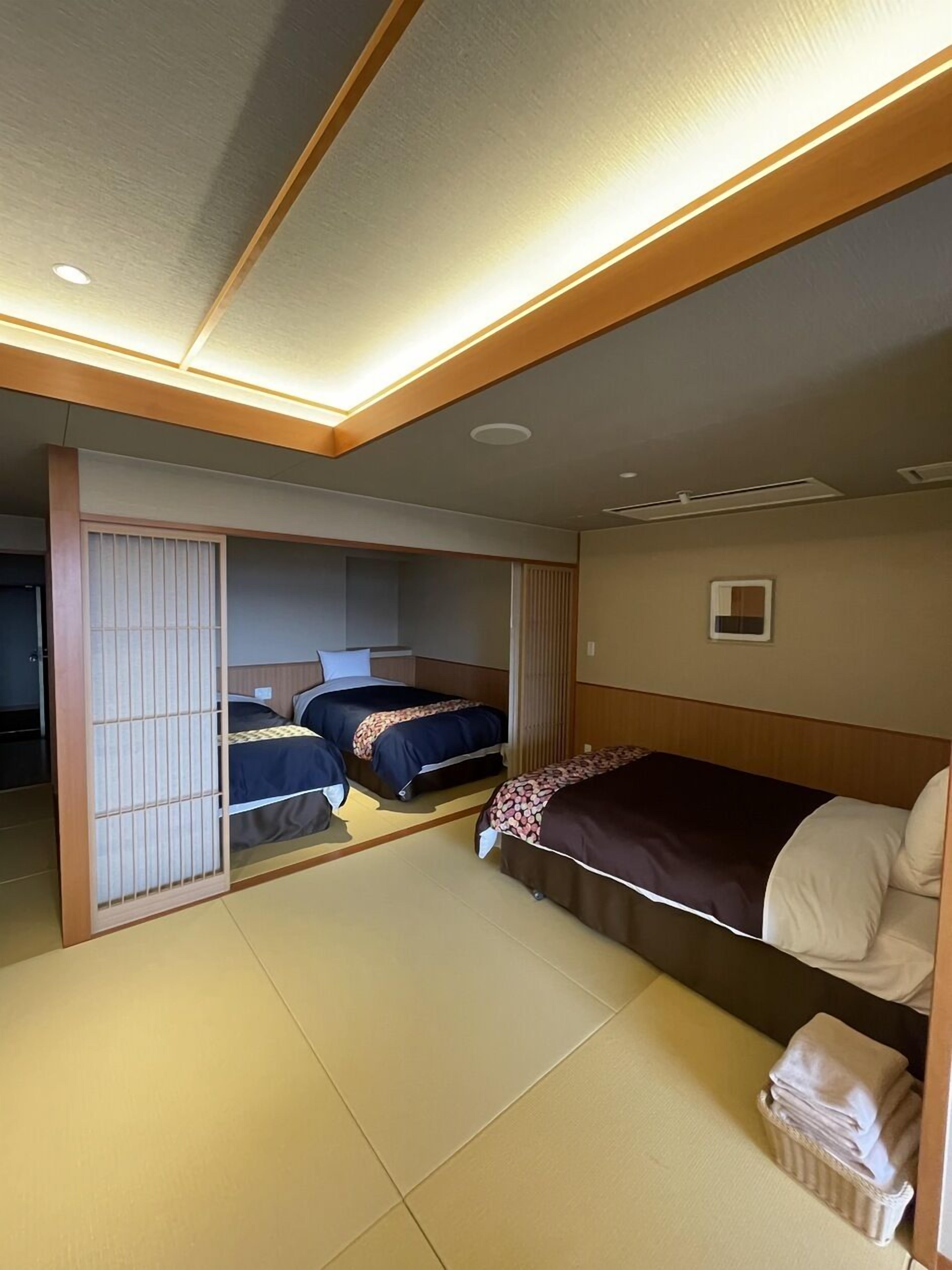 Habitació d'hotel amb dos llits, una porta corredissa i una finestra petita.