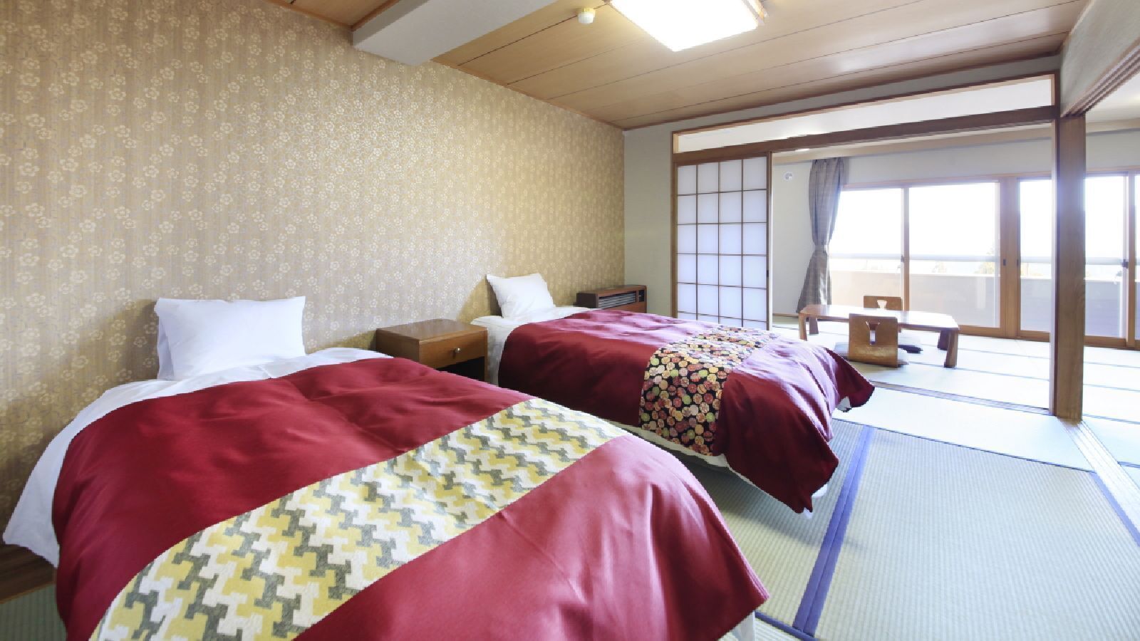Habitació d'hotel amb dos llits, sostre de fusta, porta corredissa tradicional japonesa i paviment de tatami.